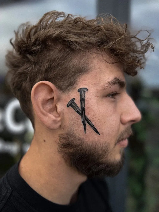 Small Blackwork Crossed Nails on Men Face Tattoo by @opalane_tatuaze