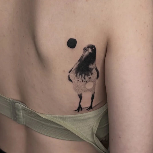 Small Blackwork Crow Tattoo on Women Back by @modul.schwarz