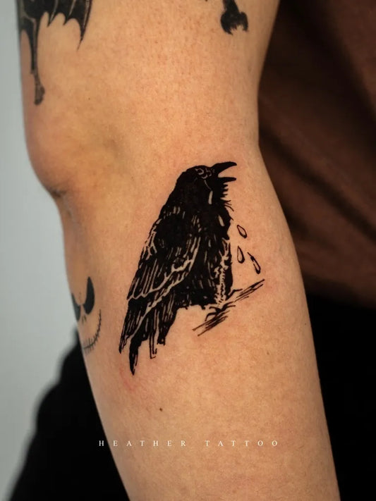 Small Blackwork Crow with Tears Tattoo on Women Arm by @heather_tattoo