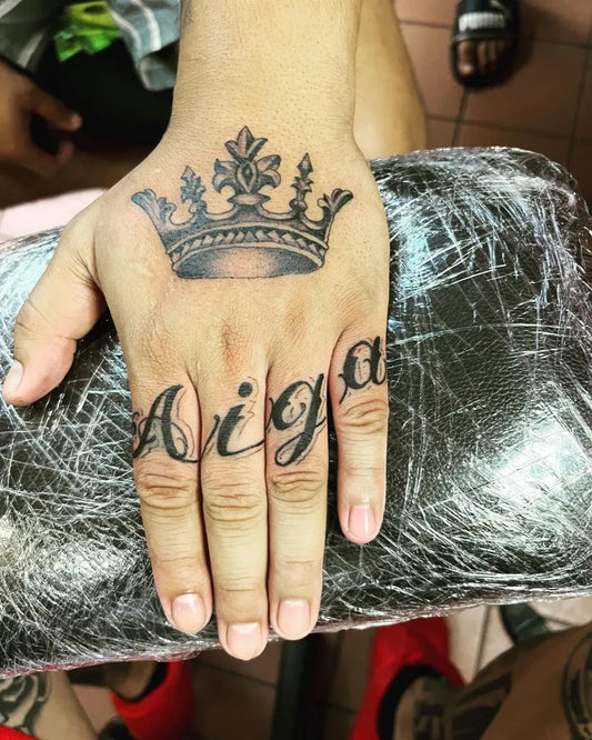 Small Blackwork Crown and Name Tattoo on Men Hand by @kriegs_christopherr