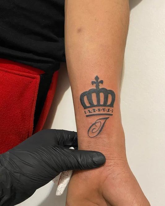 Small Blackwork Crown with Initial Tattoo on Women Wrist by @jhonnye_tattoo