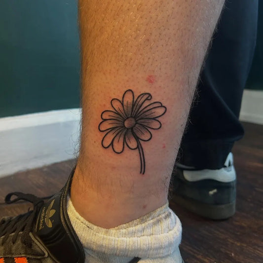 Small Blackwork Daisy Tattoo on Men Leg by @kursedtattoos