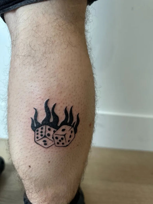 Small Blackwork Dice and Flames Tattoo on Men Leg by @simonekerr.tattoo