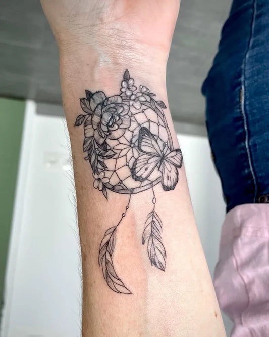 Small Blackwork Dream Catcher with Flowers and Butterfly Tattoo on Women Wrist by @agathetattoo