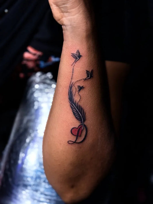 Small Blackwork Feather Heart Tattoo on Men Arm by @immortal_tattoo_madurai