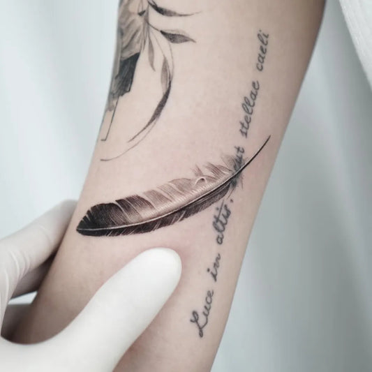 Small Blackwork Feather Text Tattoo on Women Arm by @haiirotattoo