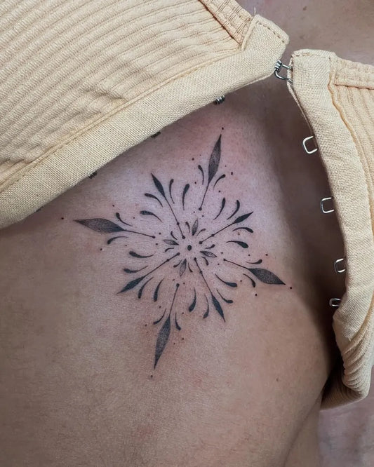Small Blackwork Floral Star on Women Sternum Tattoo by @mikel_ink_