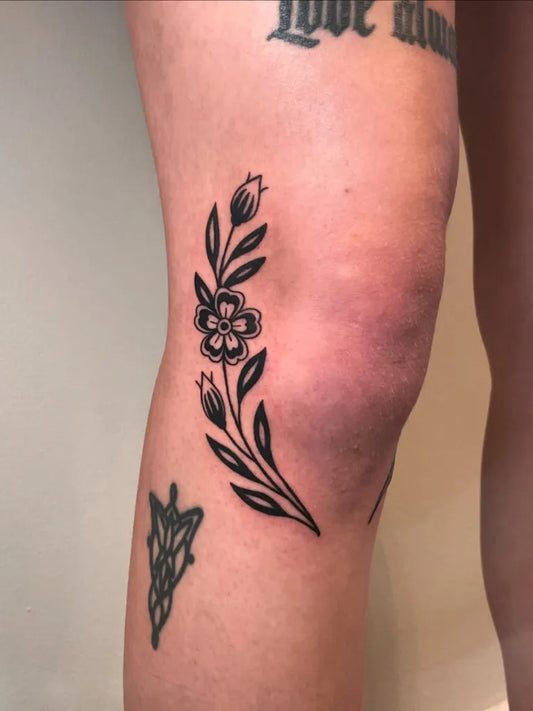Small Blackwork Flower and Bud Tattoo on Women Knee by @solaryeartattoo