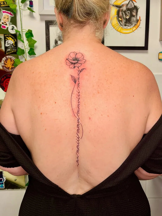 Small Blackwork Flower and Vines on Women Spine Tattoo by @willows.tatts
