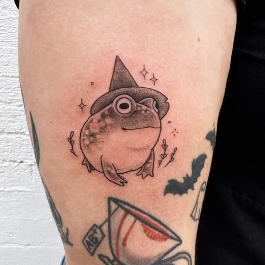 Small Blackwork Frog Witch Tattoo on Women Arm by @tiny.toad