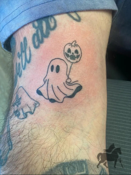 Small Blackwork Ghost with Pumpkin Balloon Tattoo on Men Arm by @apostle_tatts