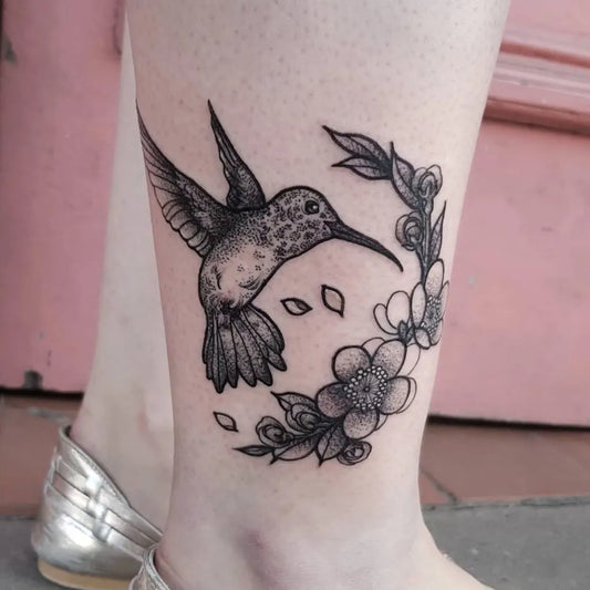 Small Blackwork Hummingbird and Floral Wreath on Women Leg Tattoo by @sola.kaida