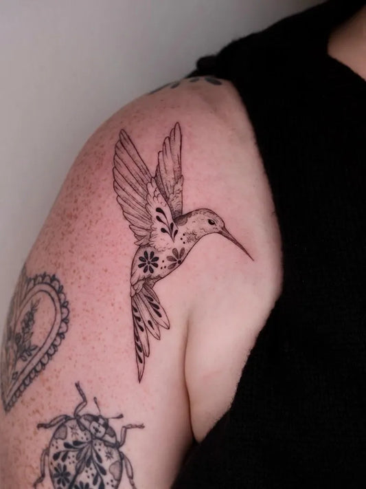 Small Blackwork Hummingbird with Flower and Ladybug on Women Shoulder Tattoo by @the.ouroboros.tattoo