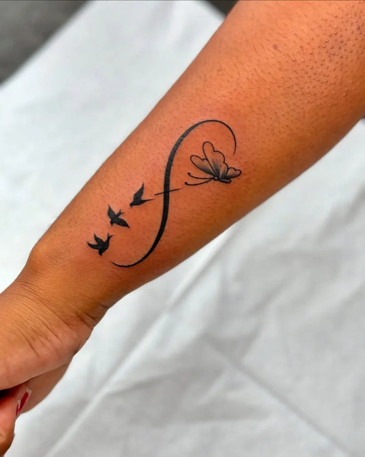 Small Blackwork Infinity Butterfly Birds Tattoo on Women Wrist by @the_tattoo_club_78