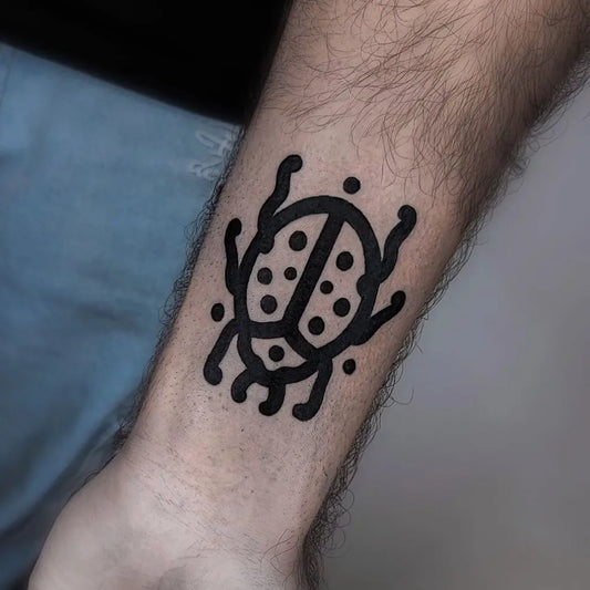 Small Blackwork Ladybug Tattoo on Men Forearm by @sailorstattoomilanomoscova