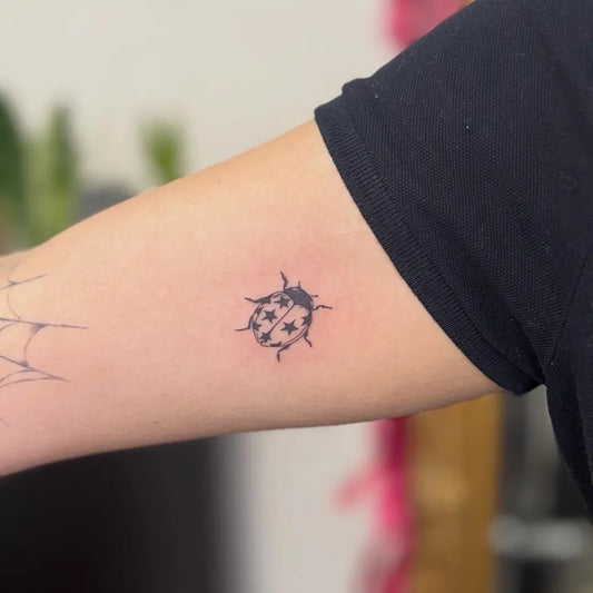 Small Blackwork Ladybug Tattoo on Women Arm by @emma.pokeya