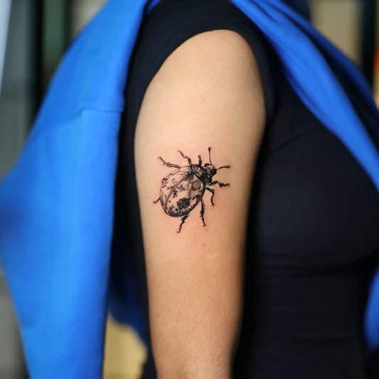 Small Blackwork Ladybug Tattoo on Women Arm by @fckthetinytattooer