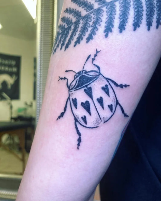 Small Blackwork Ladybug Tattoo on Women Arm by @moruse.tattoos