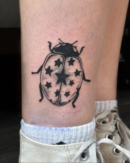 Small Blackwork Ladybug with Stars Tattoo on Women Leg by @ikaminks