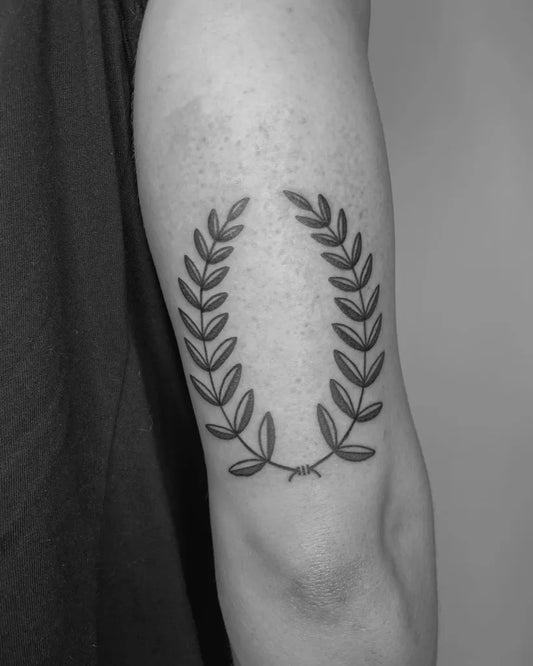 Small Blackwork Laurel Wreath Tattoo on Men Arm by @doe.ink