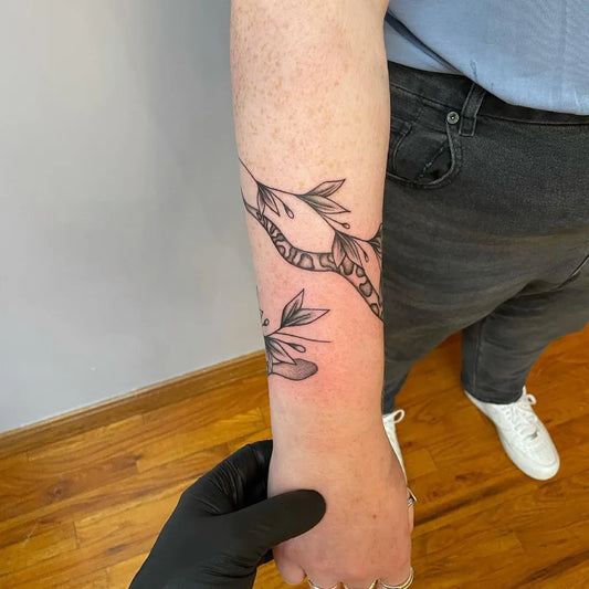 Small Blackwork Laurel Wreath with Snake Tattoo on Men Forearm by @black_lotus_tattoony