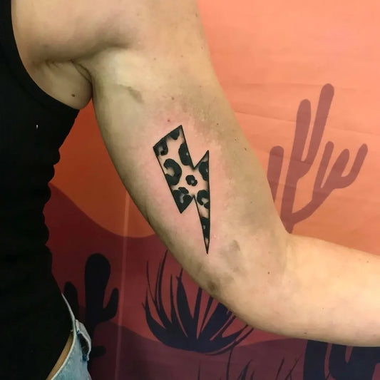 Small Blackwork Leopard Lightning Bolt Tattoo on Women Arm by @dixiebluetattoo