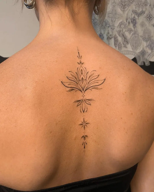 Small Blackwork Lotus Flower and Stars on Women Back Tattoo by @maye.sh