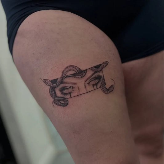 Small Blackwork Medusa Eyes with Snakes on Women Thigh Tattoo by @tink_tattoos_
