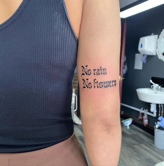 Small Blackwork No Rain Flowers Quote Tattoo on Women Arm by @drewellyntattoo