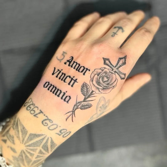 Small Blackwork Omnia Vincit Amor Cross Rose on Men Hand Tattoo by @mattiadubbioink
