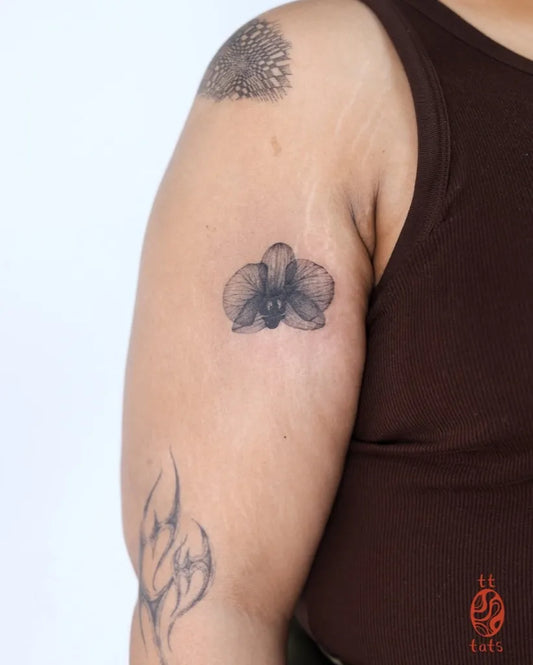 Small Blackwork Orchid Tattoo on Women Arm by @tt.tats
