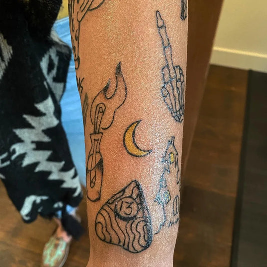 Small Blackwork OuijaBoardSkeletonFlame Halloween Tattoo on Women Arm by @abovethebartattoo