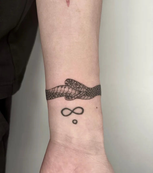 Small Blackwork Ouroboros Infinity Tattoo on Women Wrist by @nylatattoo