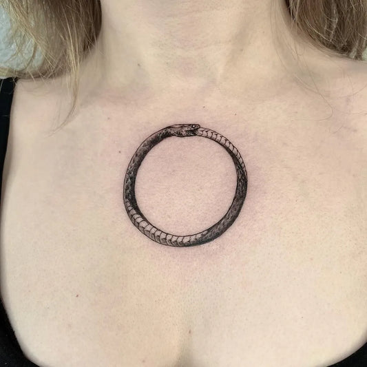 Small Blackwork Ouroboros Tattoo on Women Chest by @venus.tattooer