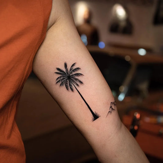 Small Blackwork Palm Tree and Mountains Tattoo on Women Upper Arm by @sebastian_tattoo
