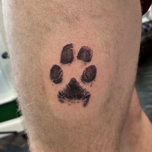 Small Blackwork Paw Print Tattoo on Men Leg by @lovetattoossandhurst
