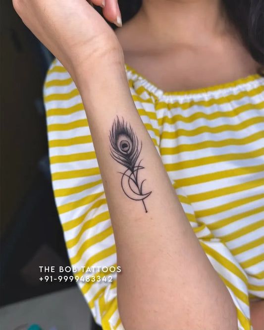 Small Blackwork Peacock Feather and Crescent Moon Tattoo on Women Wrist by @thebobtattoosindia