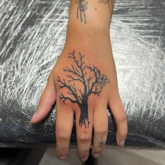Small Blackwork Poison Tree with Butterfly on Women Hand Tattoo by @inked.by.zac