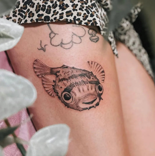 Small Blackwork Pufferfish Tattoo on Women Thigh by @idlehandstattoo_