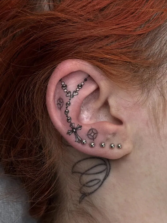 Small Blackwork Rosary and Cross Tattoo on Women Behind the Ear by @lauramayartist
