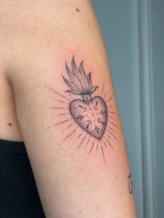 Small Blackwork Sacred Heart with Flames and Rays Tattoo on Women Upper Arm by @taleo_tattoo