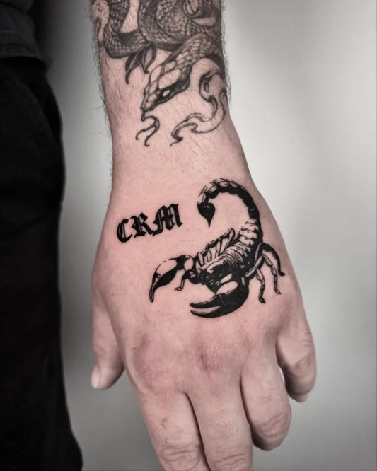 Small Blackwork Scorpion and Letters on Men Hand Tattoo by @vamos_tat