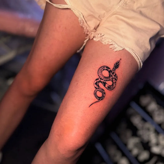 Small Blackwork Snake on Women Thigh Tattoo by @bezii_tattoo