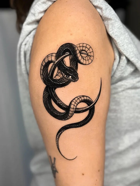 Small Blackwork Snake on Women Upper Arm Tattoo by @hudo.tt