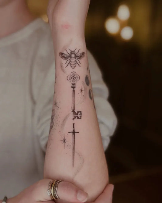 Small Blackwork Sword Key Bee on Women Forearm Tattoo by @ale.tattooart