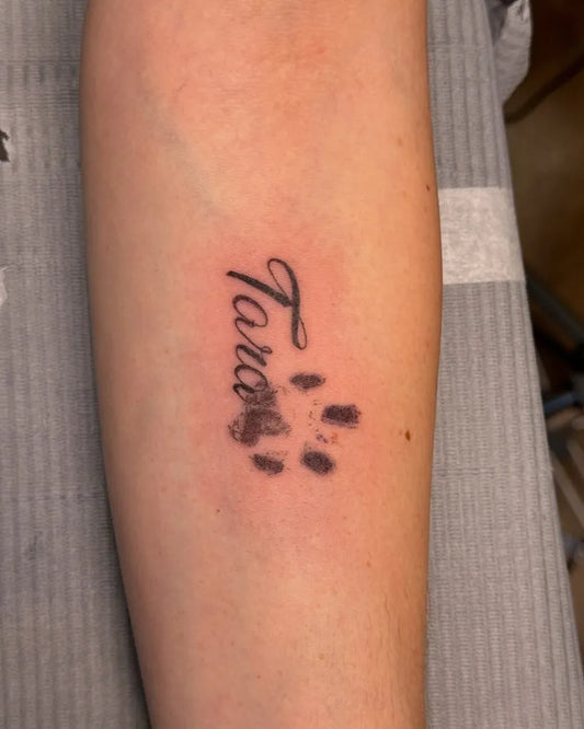 Small Blackwork Taro Name and Paw Print Tattoo on Women Forearm by @inspiredarttattoo