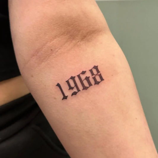 Small Blackwork Text Number Tattoo on Women Arm by @inkedby.chlo