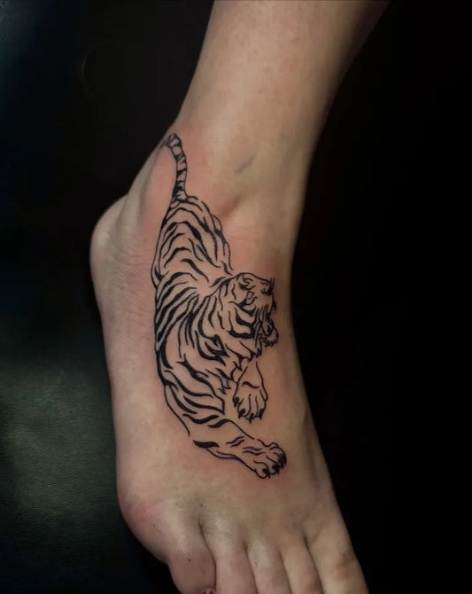 Small Blackwork Tiger on Women Foot Tattoo by @7lives.tattoo