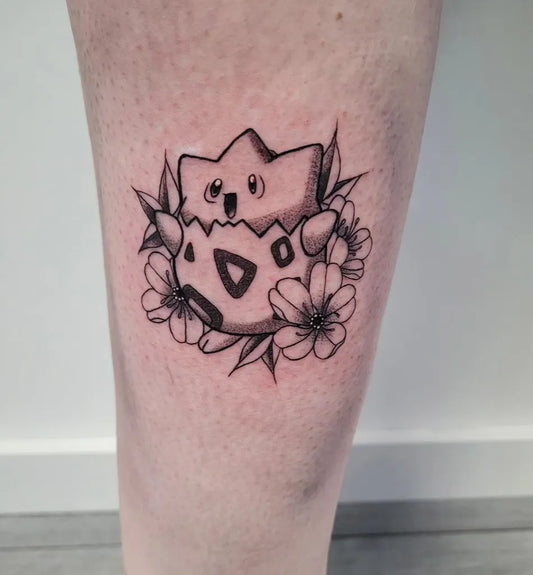 Small Blackwork Togepi with Flowers Tattoo on Women Leg by @kmbrly.art