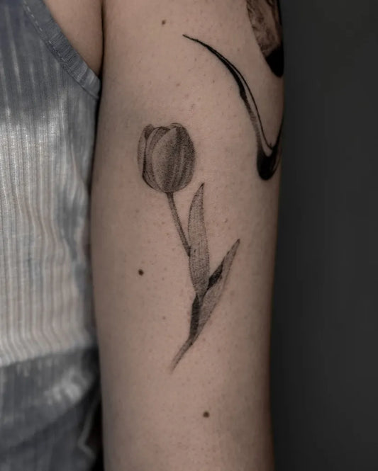 Small Blackwork Tulip and Leaves Tattoo on Women Arm by @kavi_tattoo